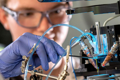 Student Simon Sprengel watches as two metal solutions enter printing nozzle.