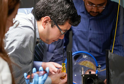 Xingjie Ni (center) manipulates a conventional telescope lens.